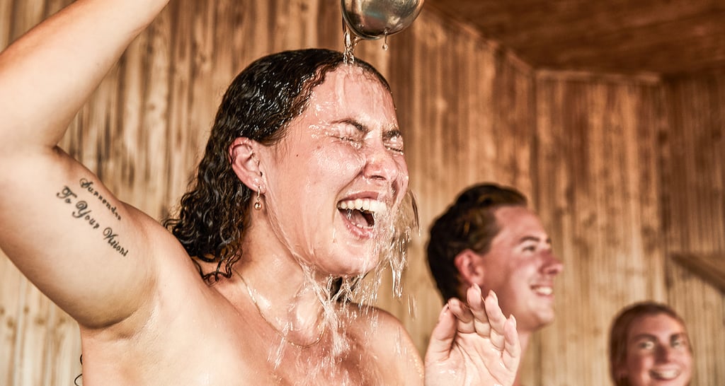 Woman pouring water over herself inside the sauna
