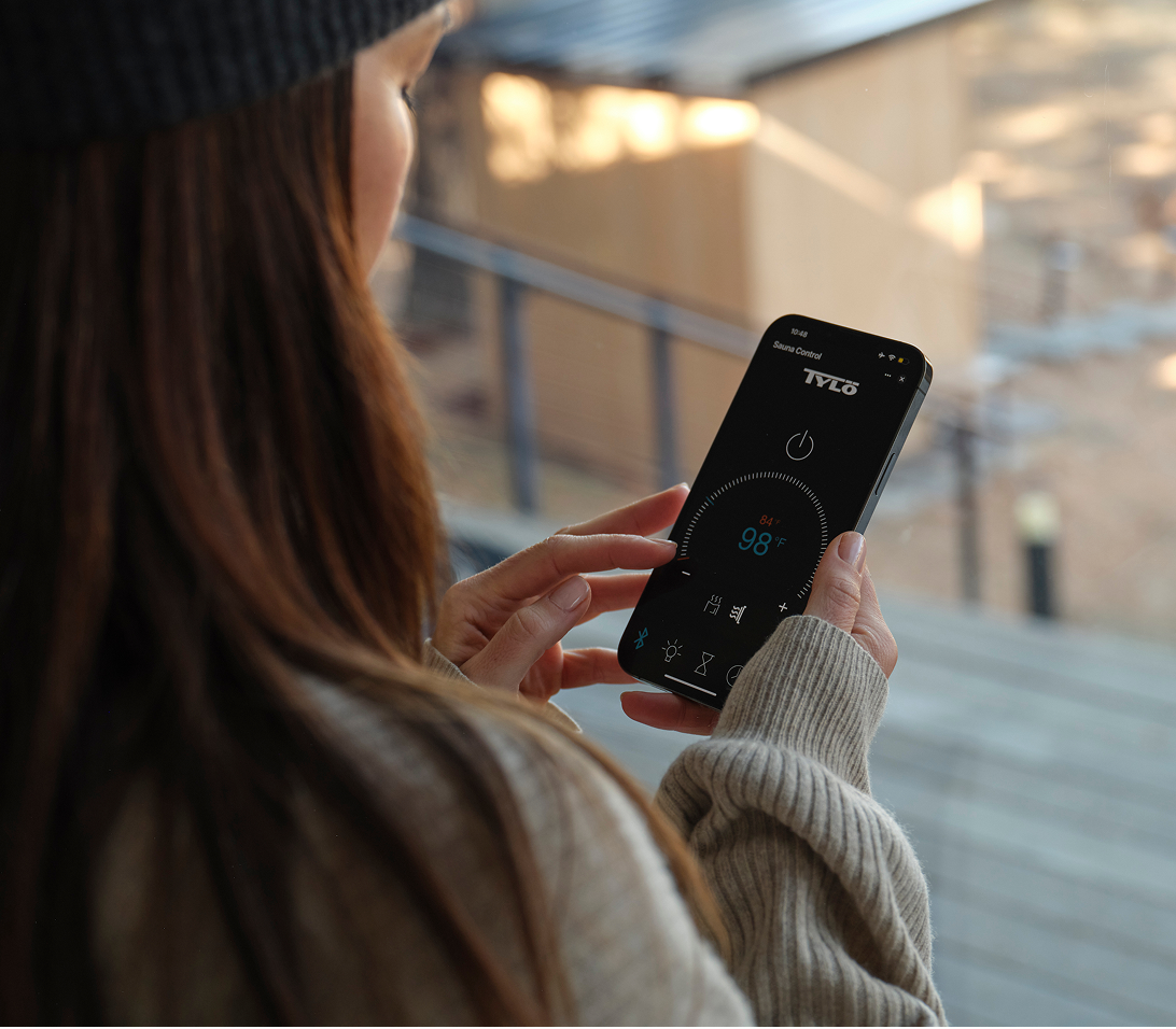 A person looking at their phone with the Tylo lifestyle app open