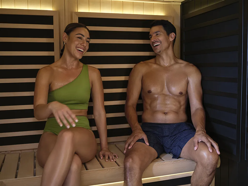 Two people sitting inside the Tylo Kiruna Hybrid sauna laughing and relaxing