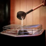a person pouring water over Tylo sauna heater