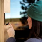 A person using a Tylo sauna digital feature outside of the sauna wearing a green hat