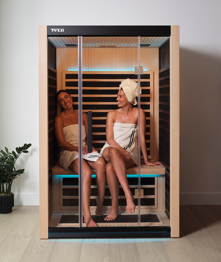 Two people sitting inside a Tylo sauna laughing and relaxing